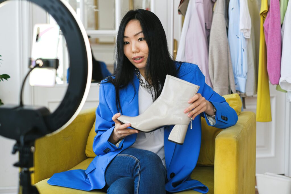 pexels-photo-6593771-6593771 Fashion influencer streaming online reviewing shoes with smartphone and lighting ring.